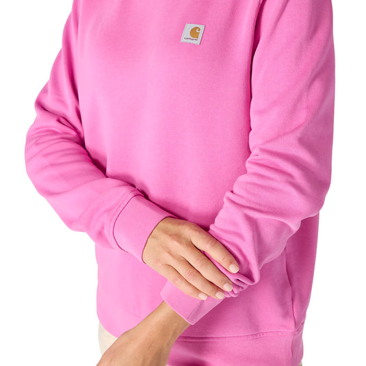 Close up of woman wearing a pink fleece crewneck sweatshirt with a Carhartt woven logo on the left chest a white background