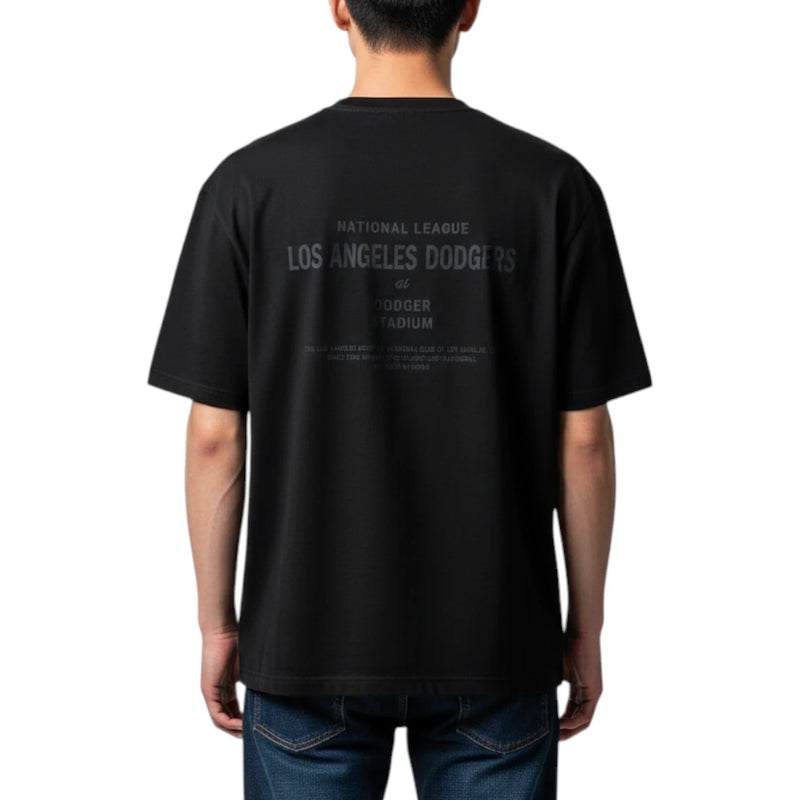 Load image into Gallery viewer, A man viewed from the back wearing a black short-sleeve t-shirt with a faded gray Los Angeles Dodgers graphic on the back, paired with blue jeans, against a plain white background.
