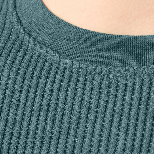 Close up of the large guage waffle knit and neck of the Dickies Women's Thermal Crewneck Shirt - Balsam Heather - This balsam fir green women's thermal shirt features a classic waffle knit fabric thermal is perfect for wearing on its own or layered under your favorite Dickies hoodies and jackets.