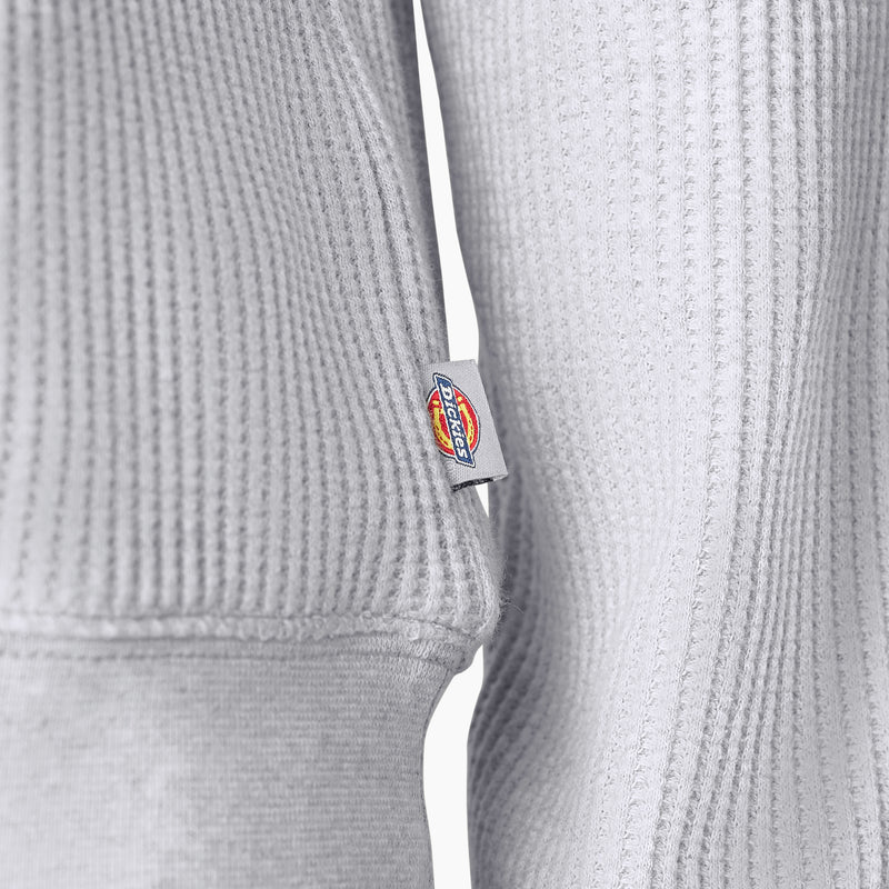 Load image into Gallery viewer, Close up of the side logo and knit of the Dickies Women's Thermal Crewneck Shirt - Light Heather Gray - This ashy gray thermal shirt features a classic waffle knit fabric thermal is perfect for wearing on its own or layered under your favorite Dickies hoodies and jackets.
