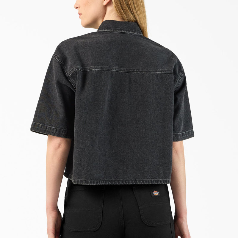 Load image into Gallery viewer, The back of a model wearing a black boxy, cropped women's Dickies denim short sleeve work shirt that is sandwashed for vintage look and a worn-in feel.
