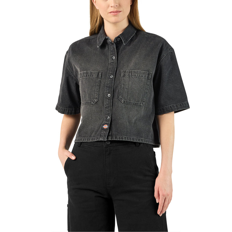 Load image into Gallery viewer, A model wearing a black boxy, cropped women's Dickies denim short sleeve work shirt that is sandwashed for vintage look and a worn-in feel.
