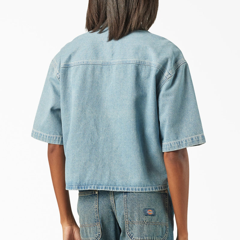 Load image into Gallery viewer, The back of a model wearing a light blue boxy, cropped women's Dickies denim short sleeve work shirt that is sandwashed for vintage look and a worn-in feel.
