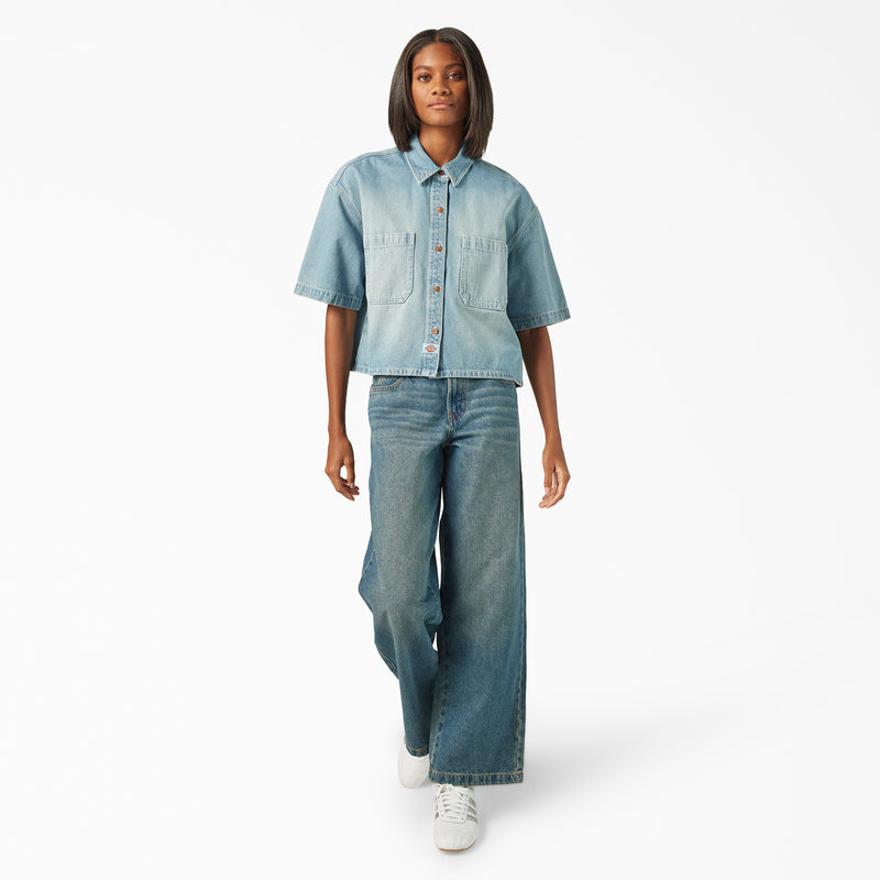 Load image into Gallery viewer, A model wearing a light blue boxy, cropped women's Dickies denim short sleeve work shirt that is sandwashed for vintage look and a worn-in feel.
