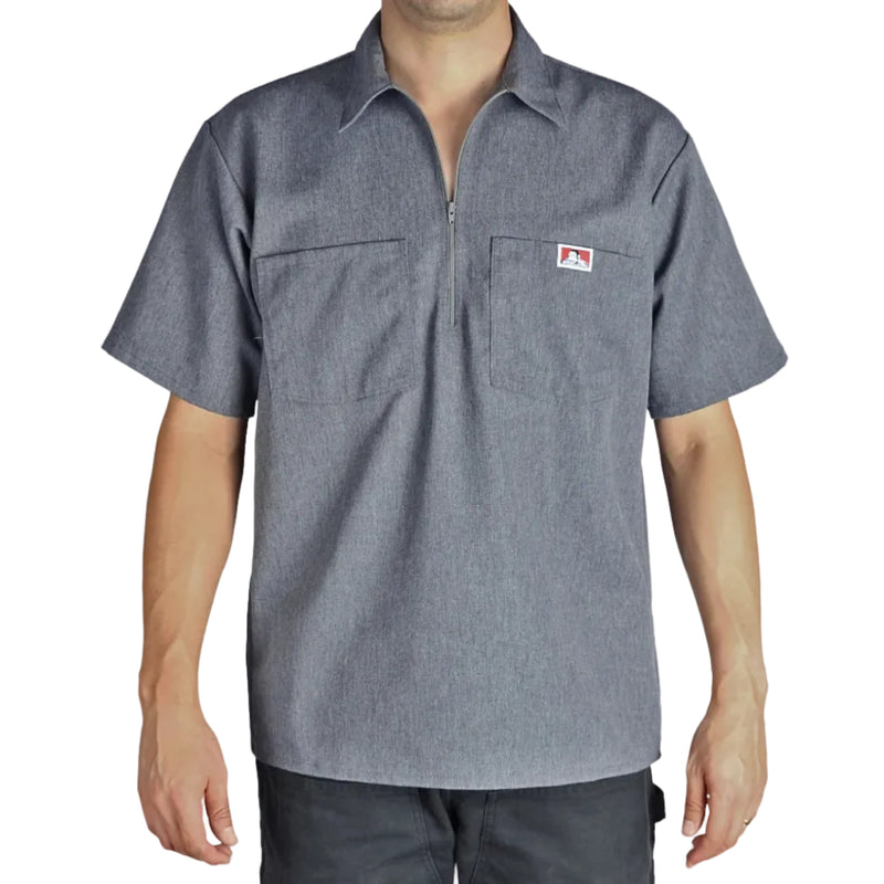 Load image into Gallery viewer, Person wearing a charcoal heather half zip short-sleeve shirt with a logo on the left chest pocket on a white background
