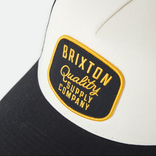 Black and off white cap with a yellow and black Brixton logo patch.