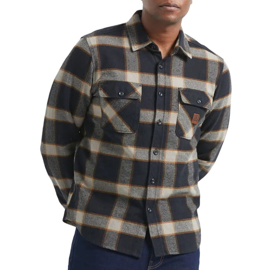 Man wearing a plaid shirt and dark jeans on a white background