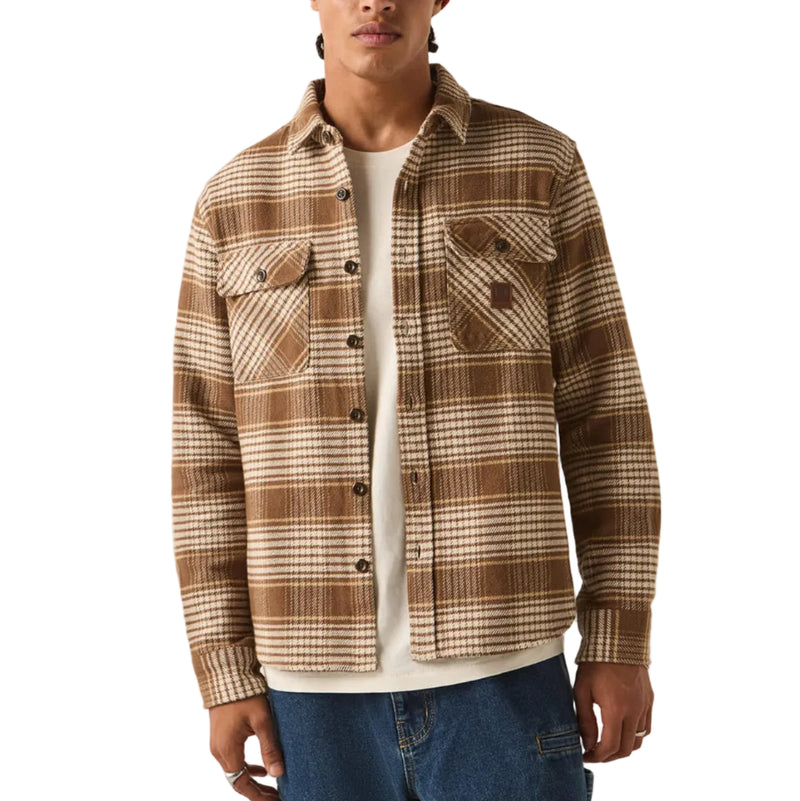 Load image into Gallery viewer, A model wearing a brown and beige plaid button-up overshirt over a white t-shirt, blue jeans, and a red knit beanie, standing against a plain off-white background.
