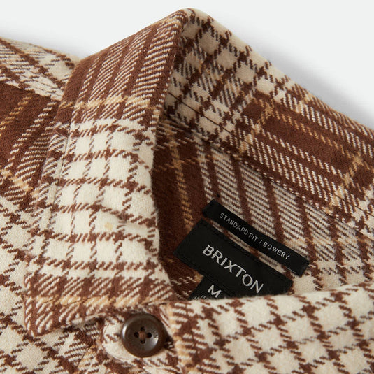 Close-up of a Brixton plaid shirt collar showing the brown and cream pattern, with the black brand label visible.