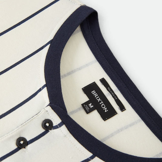 Close-up of a striped henley shirt by Brayton, featuring a cream base with navy blue stripes and a solid navy ribbed collar and button placket.