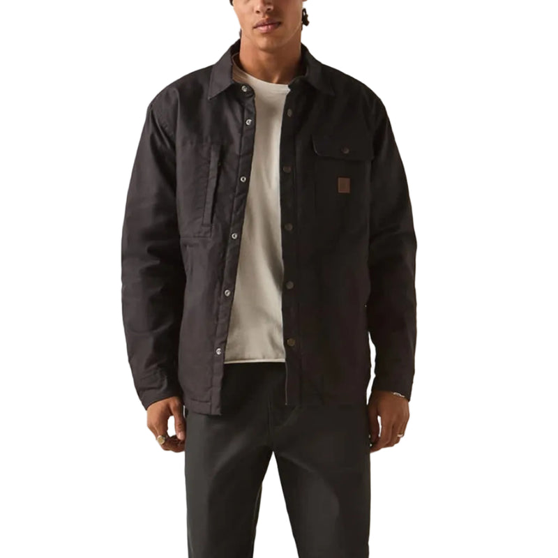 Load image into Gallery viewer, A man modeling a dark charcoal work jacket over a white t-shirt, paired with dark gray pants, black shoes, and a red beanie, standing against a plain off-white studio background.
