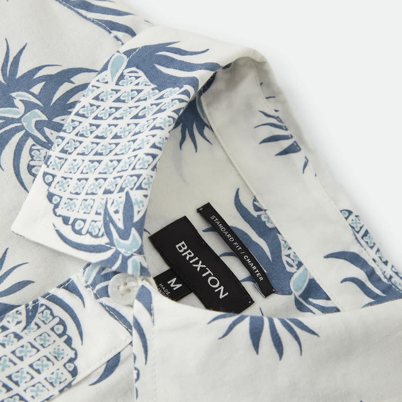 Load image into Gallery viewer, Close-up of a white short-sleeve button-up shirt with a blue and light blue pineapple print, featuring a black BRIXTON neck label.
