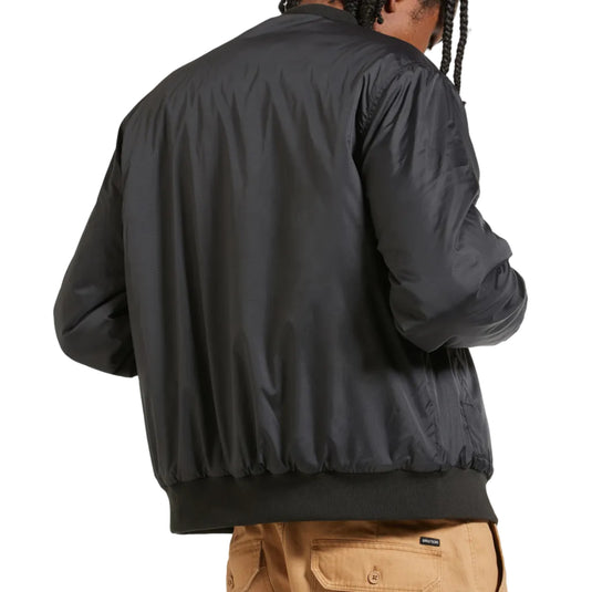 A person shown from the back wearing a black lightweight bomber-style jacket and tan cargo pants against a plain white background.