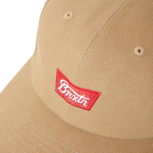 Close up of the embroidered red and white logo on a khaki cap. The Stith Adjustable Hat is a versatile everyday staple featuring a semi-structured 6-panel design and a curved bill for a timeless, classic look. 