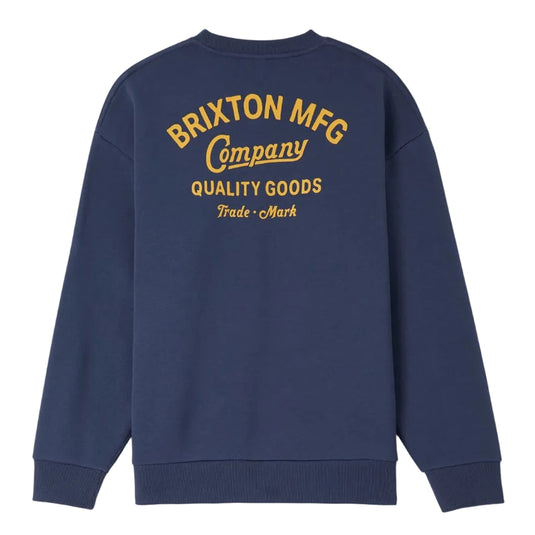 A navy blue crewneck sweatshirt shown from the back, featuring a large yellow graphic print that reads 'BRIXTON MFG Company QUALITY GOODS Trade Mark'.