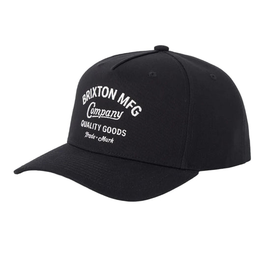 A black baseball cap with white embroidered text reading 'Brixton MFG Company Quality Goods' on the front, shown against a light gray background.