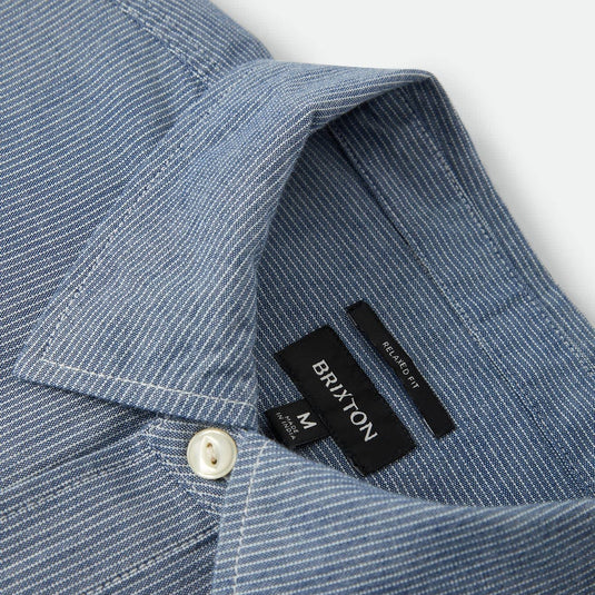 Closeup on the collar of a light blue striped Brixton button up shirt