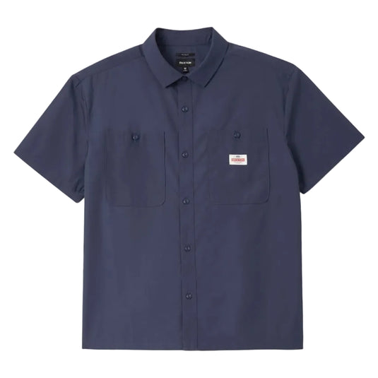 A navy blue short-sleeve button-up shirt with a pointed collar, two chest pockets, and a small red and white logo patch on the left chest, displayed against a light gray background.