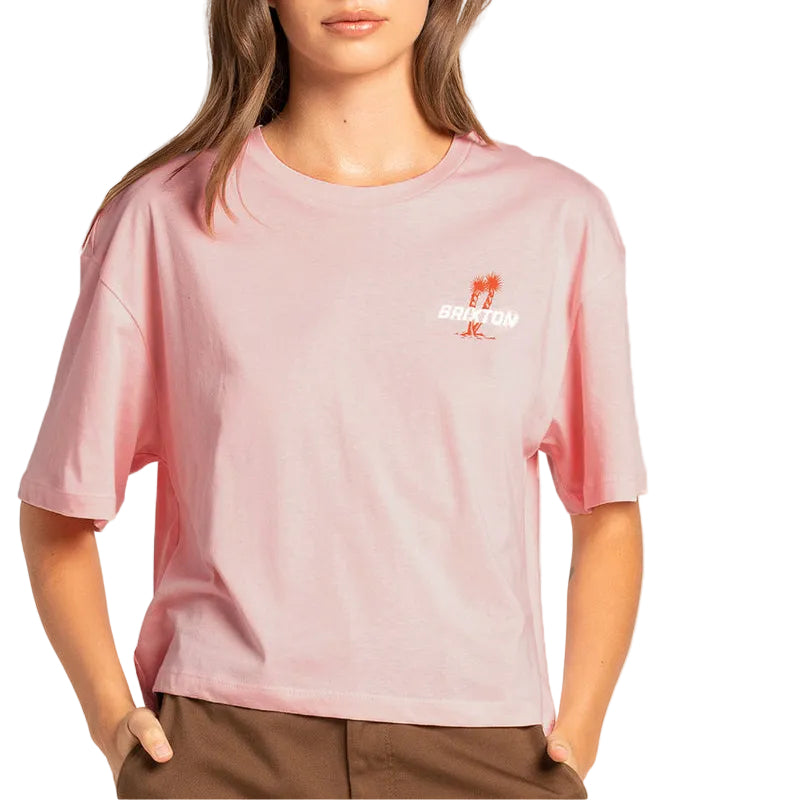 Load image into Gallery viewer, A woman wearing a light pink short-sleeve t-shirt with a small orange and white graphic on the left chest, paired with brown pants, against a plain white background.
