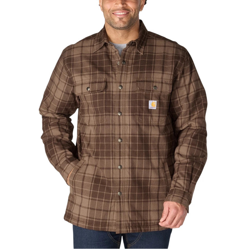 Load image into Gallery viewer, A man wearing a brown Carhartt plaid button-up shirt jacket over a gray t-shirt and blue jeans, standing against a solid white background.
