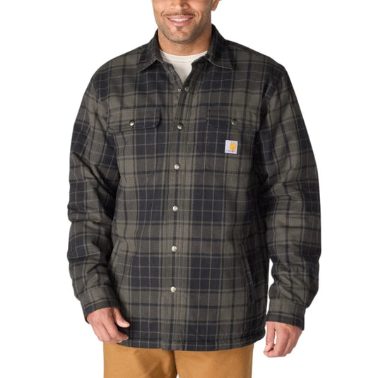 A man wearing a dark gray and black plaid Carhartt work shirt over a white undershirt, paired with tan pants, against a plain white background.
