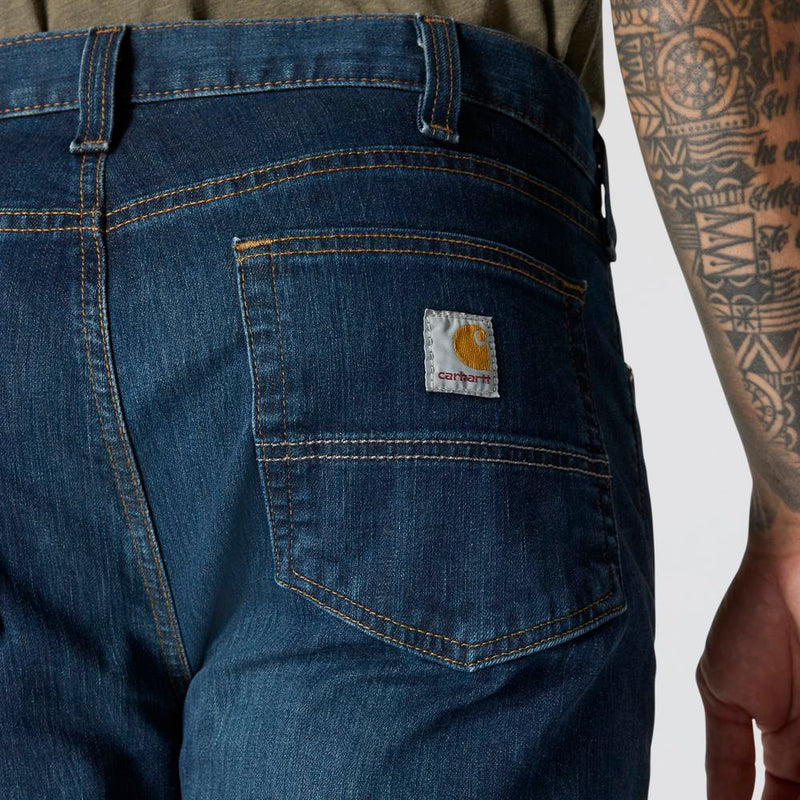 Load image into Gallery viewer, Close-up of blue jeans with a Carhartt logo on a white background
