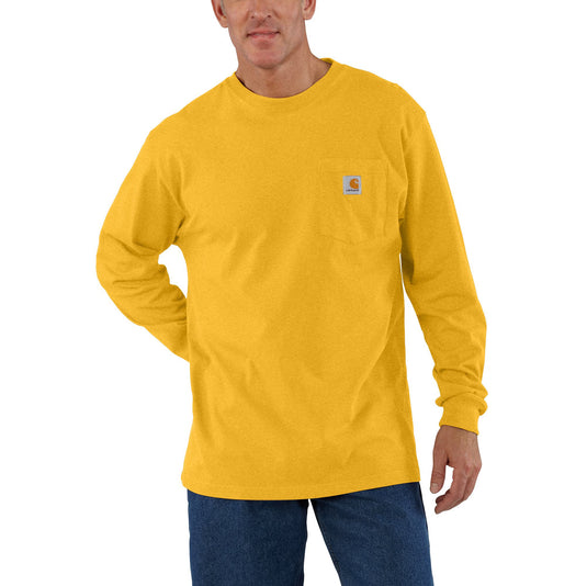 A man wearing a yellow long-sleeve pocket t-shirt with a small Carhartt logo on the chest pocket, paired with dark blue jeans, against a plain white background.