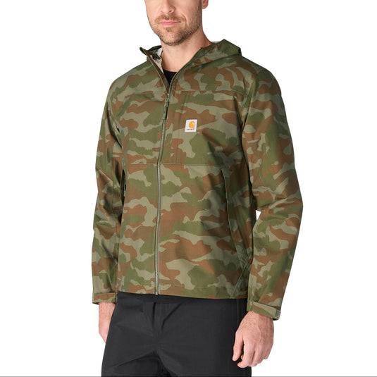 A man wearing a camouflage hooded jacket with a full zipper and a small Carhartt logo patch on the chest, paired with black pants, against a plain white background.