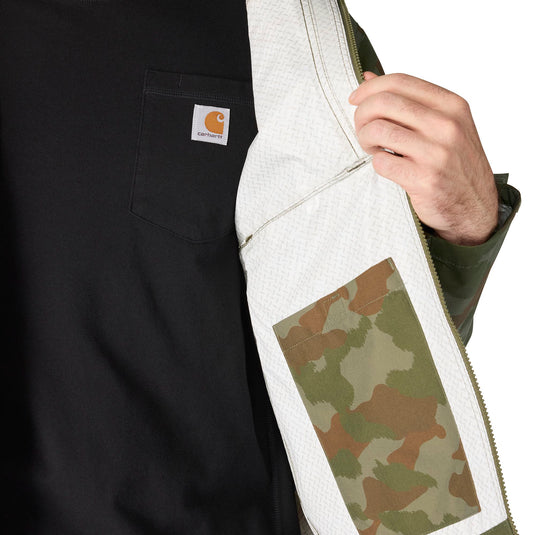 Close-up of a person wearing a black Carhartt work jacket, showing the white quilted inner lining, a camouflage patch pocket, and the Carhartt logo on the chest pocket.