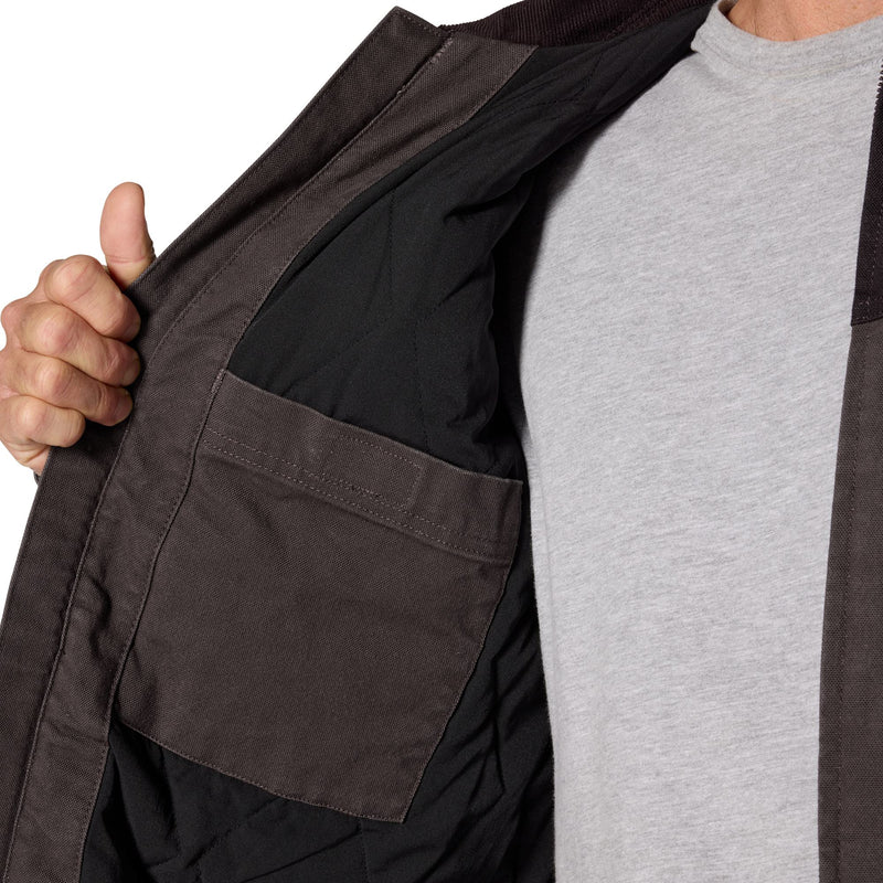 Load image into Gallery viewer, Close-up of a person wearing a dark brown utility jacket over a light gray t-shirt, with the hand opening the jacket to show the black interior lining and pocket.
