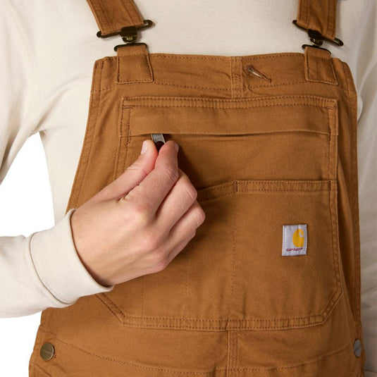 Close up of Carhartt Brown overalls with front chest pocket with a zipper and a visible Carhartt logo on the left pocket on a white background