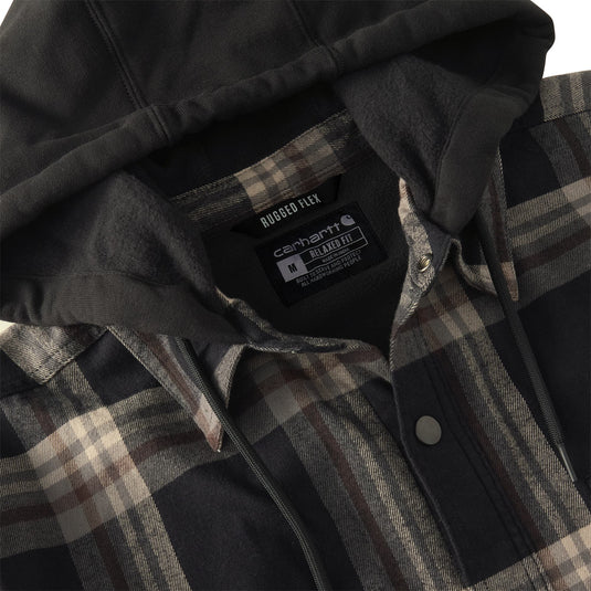 Close-up of a Carhartt flannel shirt with a dark gray hood and a black, gray, and beige plaid pattern. The inner neck label clearly shows the Carhartt brand and 'Rubbed Flex' technology.