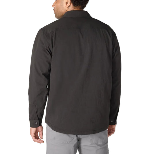 A man viewed from the back wearing a dark charcoal gray long-sleeve button-up shirt and light gray pants, set against a plain white background.