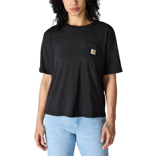 A woman with curly black hair wearing a black Carhartt short-sleeve crewneck t-shirt with a chest pocket and light blue jeans, standing against a solid white background.