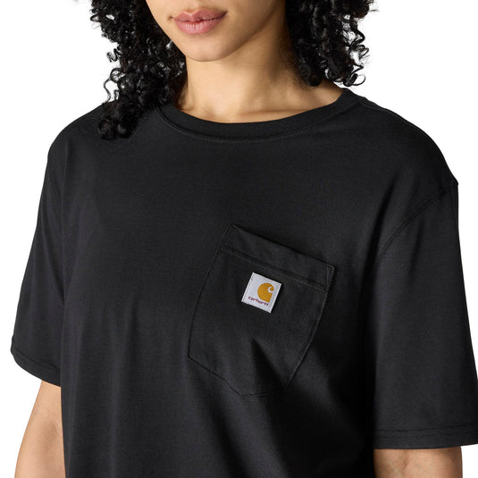 A close-up of a person wearing a black short-sleeve crewneck t-shirt with a chest pocket featuring a square Carhartt logo patch.