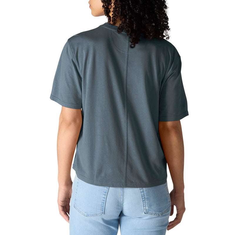 Load image into Gallery viewer, A woman viewed from the back wearing a slate blue-gray short-sleeve t-shirt and light blue jeans against a plain white background.
