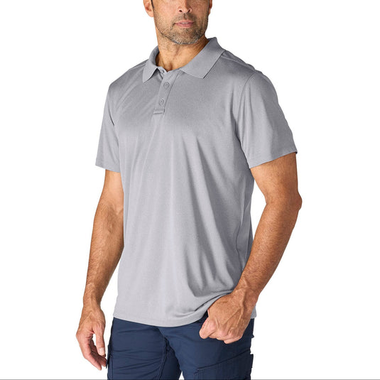 A man wearing a light gray short-sleeve polo shirt and navy pants, standing against a plain white background.
