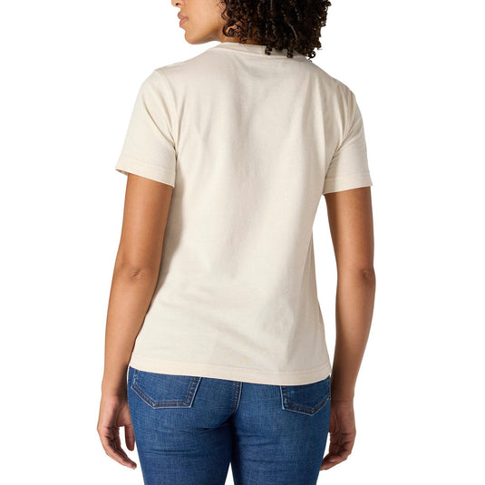 A woman with curly dark hair is shown from the back wearing a short-sleeve crewneck t-shirt in a warm off-white/cream color, paired with blue jeans, against a solid white background.