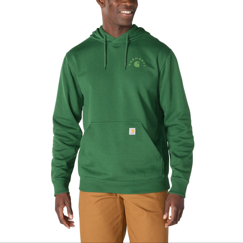 Load image into Gallery viewer, A man wearing a green Carhartt pullover hoodie with a small embroidered Carhartt logo on the left chest and a small orange brand tab on the front pocket, paired with tan pants, against a plain white background.
