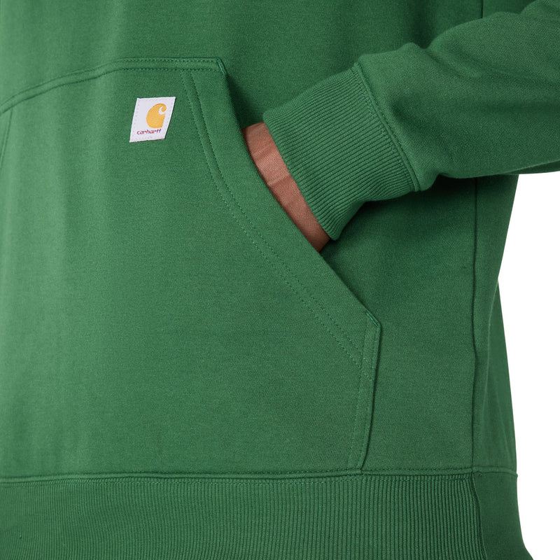Load image into Gallery viewer, Close-up of a green Carhartt hoodie with a front pocket and a hand reaching into the pocket, showing the Carhartt brand tag.
