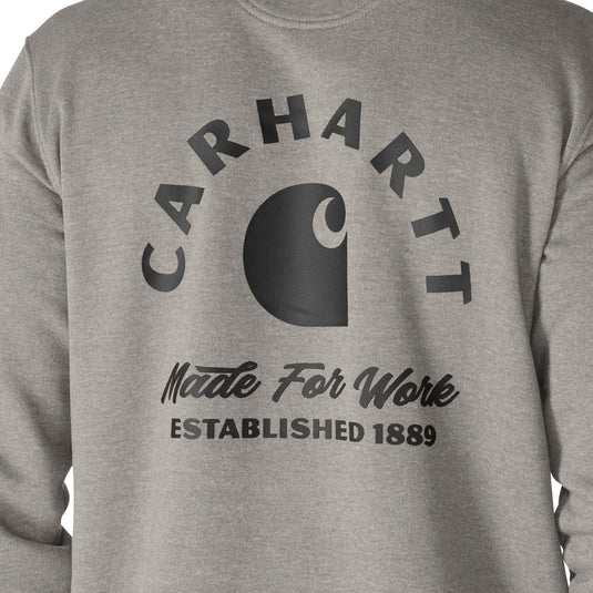Close-up of a heather gray sweatshirt featuring a large black Carhartt logo and text on the front, including 'CARHART', 'Made For Work', and 'ESTABLISHED 1889'.