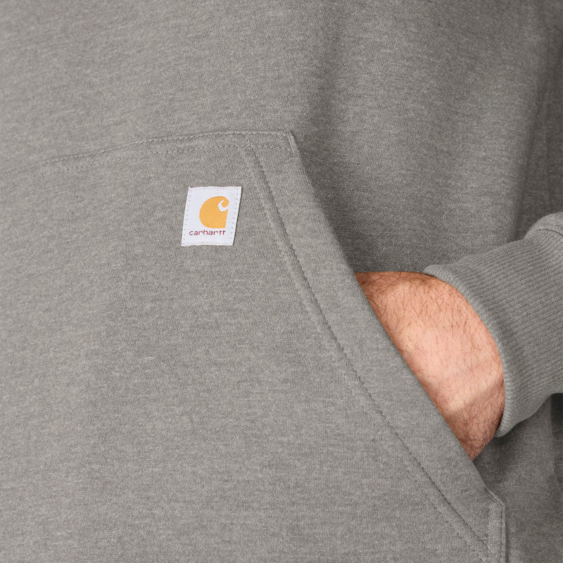 Load image into Gallery viewer, Close-up of a heather gray Carhartt hoodie pocket with the brand's signature square logo patch, showing a hand reaching into the pocket.
