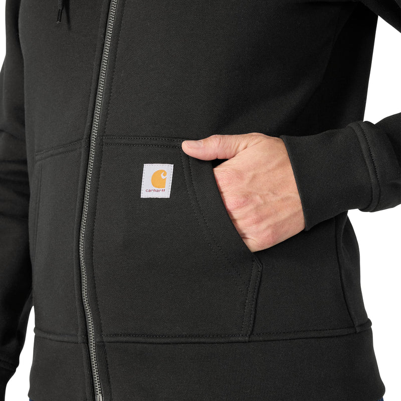 Load image into Gallery viewer, Close-up of a person wearing a black zip-up hoodie with a front pocket and a visible Carhartt logo patch on the pocket.
