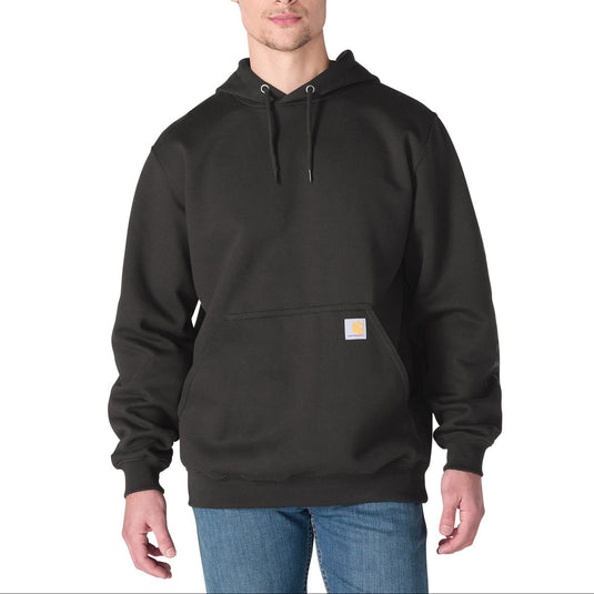 A man wearing a black Carhartt pullover hoodie with a small signature Carhartt logo patch on the front pocket, paired with blue jeans, against a plain white background.