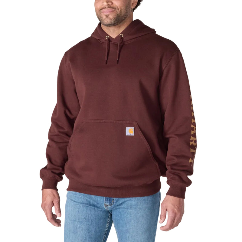 Load image into Gallery viewer, A man wearing a maroon Carhartt pullover hoodie with a drawstring hood, kangaroo pocket, and a patterned sleeve, paired with blue jeans, against a plain white background.
