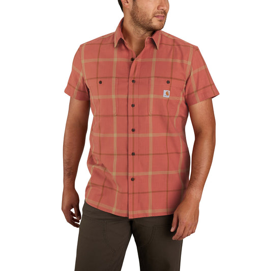 Model wearing a terracotta-colored plaid short sleeve button up collared shirt on a white background. 