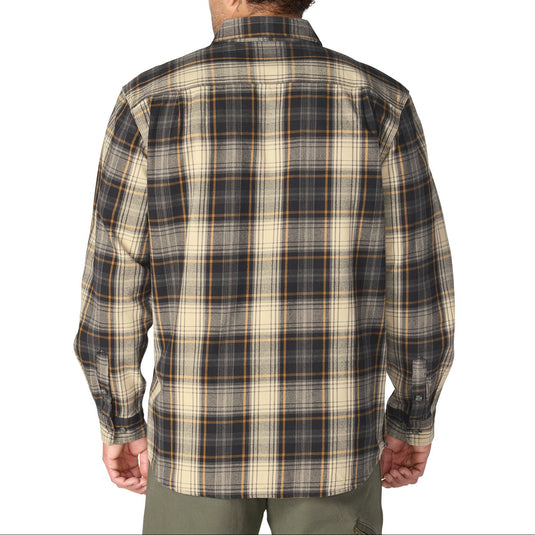 A man viewed from behind wearing a long-sleeve plaid flannel shirt in beige, black, and brown tones, paired with olive green pants, against a plain white background.