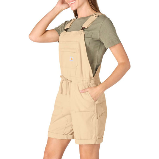 Woman wearing beige Carhartt shortalls and a green shirt on a white background