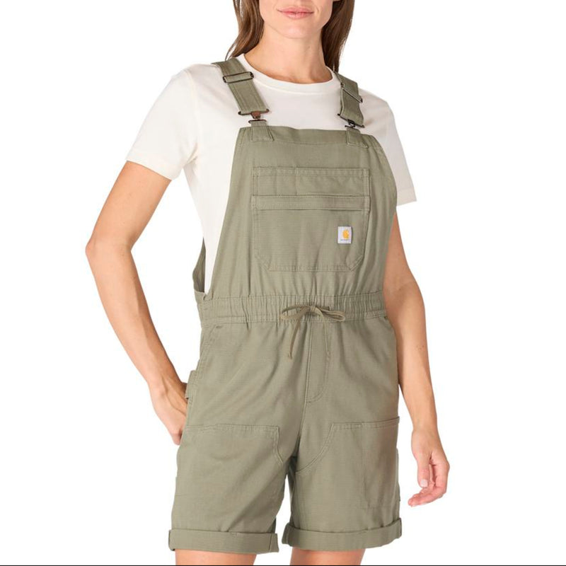 Load image into Gallery viewer, Woman wearing a green Carhartt bib shortalls with a white shirt underneath on a white background
