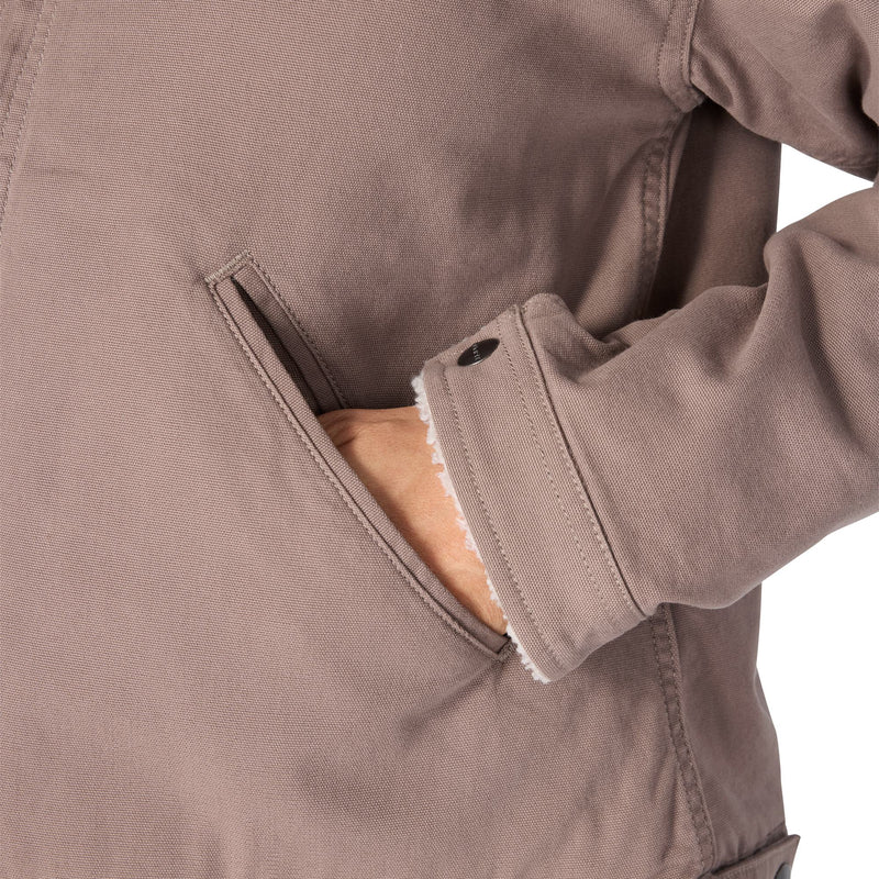 Load image into Gallery viewer, Close-up of a taupe-brown utility jacket with a side pocket, showing a hand reaching into the pocket and the interior fleece lining.
